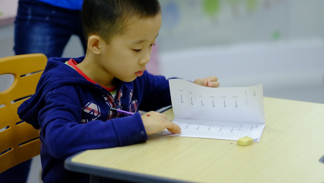 a young boy sitting at a table writing on a piece of paper