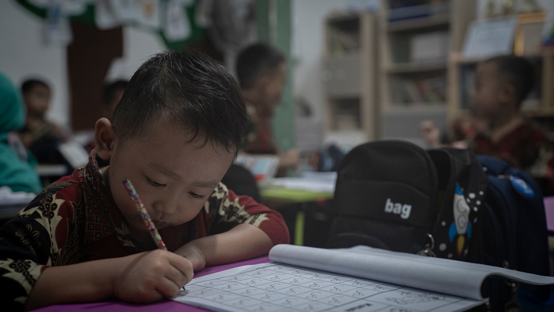 A young boy sitting at a table writing on a paper