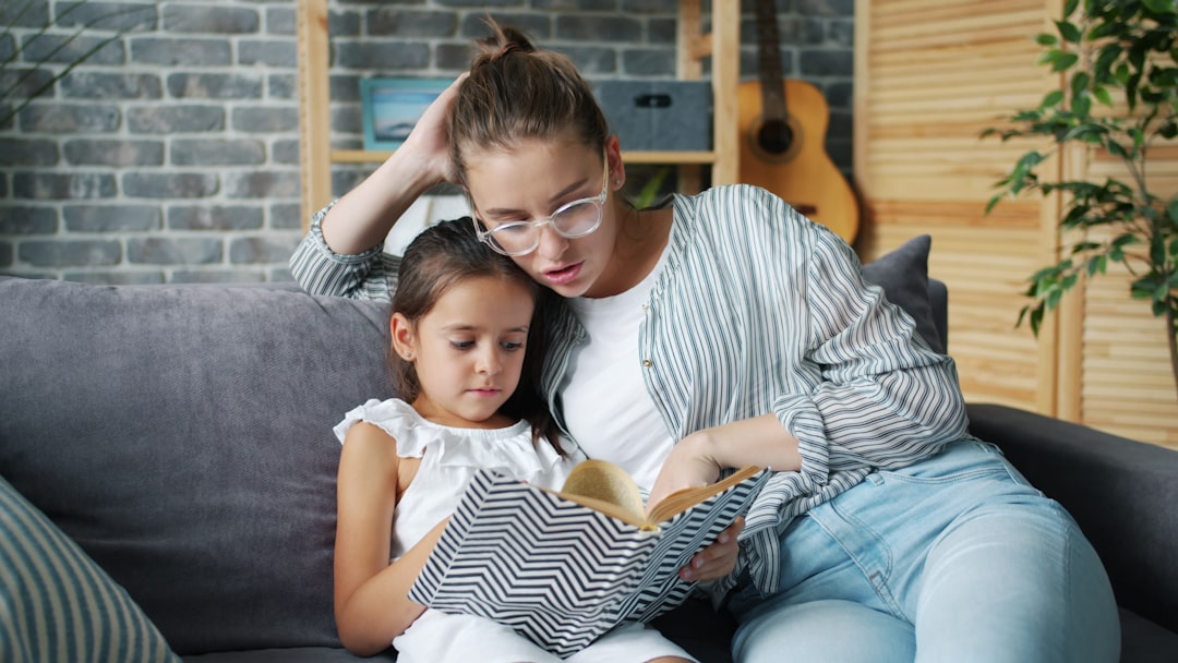 Happy young family mother and daughter are reading children's book at home smiling enjoying time together. Apartment, culture and childhood concept.
