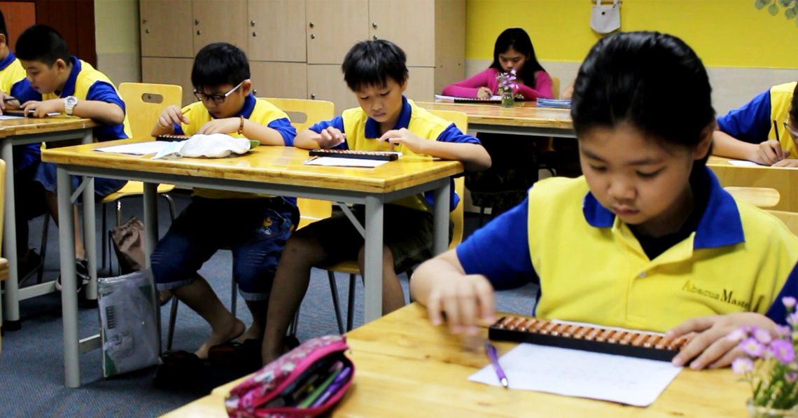 Trẻ em châu Á đang học Soroban với bàn tính tại nhà