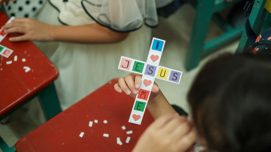 A child is making a handicraft in the shape of a cross and saying I love Jesus