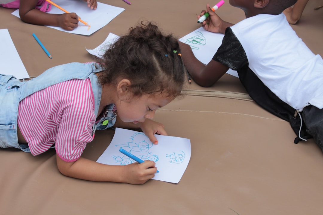 girl in pink and white stripe shirt writing on white paper